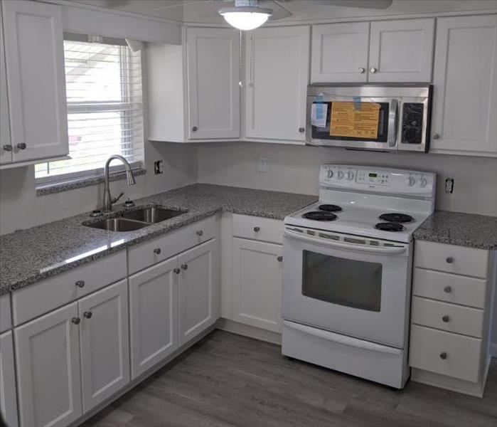 Kitchen with white cabinets and appliances and grey flooring