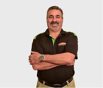 Male in black polo standing in front of light background